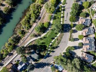 Experience luxury living with this stunning aerial view showcasing modern townhomes nestled beside a serene river and scenic walking trails.