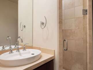 This modern bathroom features a sleek vessel sink with chrome fixtures, complemented by a large vanity mirror.