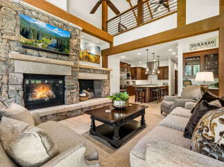 Experience luxury mountain living in this stunning great room, featuring a massive stone fireplace and a large TV perfect for cozy evenings.