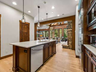 Experience luxury mountain living in this stunning kitchen, featuring a large island with a marble countertop and a built-in dishwasher.