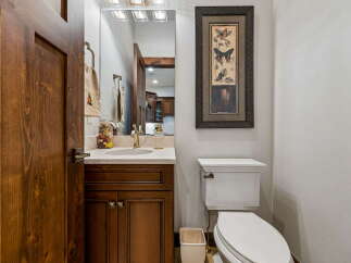 This powder room features a beautiful wooden vanity with a marble countertop and a modern brass faucet.