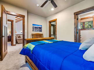This inviting bedroom features a comfortable queen-size bed with vibrant blue bedding and a cozy throw blanket.