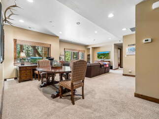 This spacious living area offers a cozy dining nook with a rustic wooden table and plaid chairs, perfect for intimate meals.