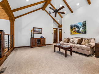 Experience rustic charm in this spacious living area, featuring vaulted ceilings with exposed wooden beams and a cozy fireplace.