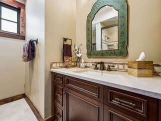 This elegant bathroom features a dark wood vanity with a light countertop and a decorative mosaic tile backsplash.