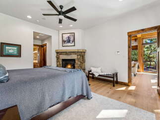 Experience ultimate comfort in this luxurious bedroom, featuring a cozy stone fireplace and a plush king-sized bed.