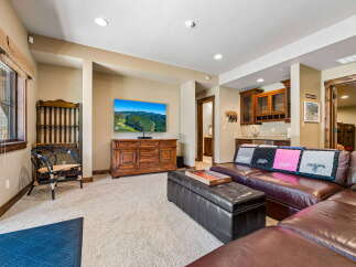 This inviting living space features a large sectional sofa perfect for gatherings, complemented by a stylish leather ottoman and a rustic wooden entertainment center.