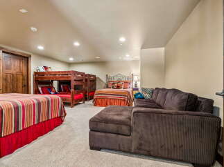 This spacious basement bedroom offers ample sleeping arrangements with a twin-over-twin bunk bed and two additional twin beds, perfect for accommodating large families or groups.