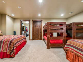 This spacious bedroom features a cozy single bed with a bear-themed pillow and a vibrant striped comforter, perfect for a comfortable stay.