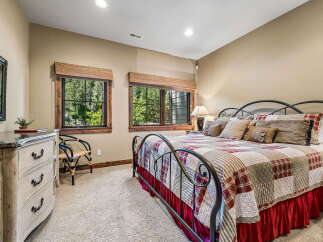 Experience rustic charm in this cozy bedroom featuring a comfortable queen-size bed adorned with a charming patchwork quilt.