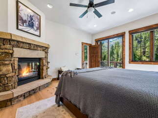 Experience rustic luxury in this stunning bedroom featuring a grand stone fireplace, perfect for cozy evenings.