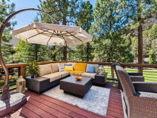 Enjoy outdoor living on this spacious deck, complete with a comfortable sectional sofa, a stylish coffee table, and a large cantilever umbrella for shade.