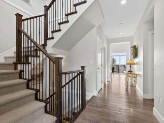 Step into this elegant home featuring a grand staircase with rich wood banisters and intricate metal spindles.