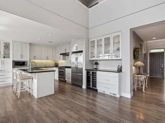 Experience luxury and functionality in this stunning modern kitchen, featuring sleek white cabinetry, a spacious island with seating, and high-end stainless steel appliances.