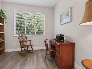 This charming home office features a vintage wooden desk with a typewriter, a comfortable rocking chair, and a tall bookshelf filled with decorative items.