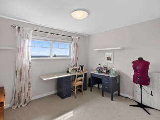 This bright and airy room is perfect for any crafter or seamstress, featuring a dedicated sewing station with a sewing machine and ample desk space.