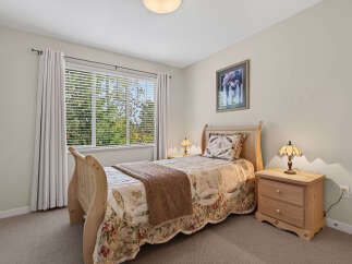 This charming bedroom features a cozy bed with a floral quilt and a warm brown throw, perfect for relaxation.