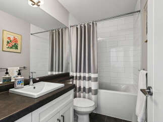 This modern bathroom features a sleek vanity with a white undermount sink and a chrome faucet, complemented by decorative soap dispensers.