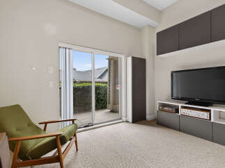 This living room features a comfortable green armchair positioned near a sliding glass door that opens to an outdoor patio.