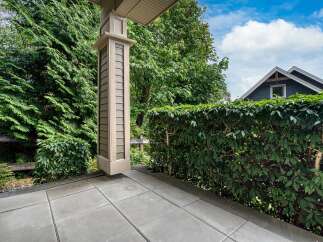 Enjoy the outdoors from this charming covered porch, featuring a decorative column and a paved patio area.