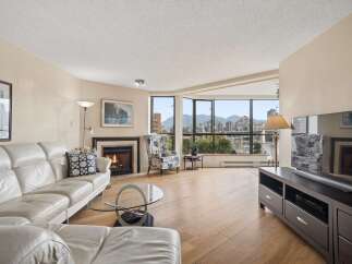 Experience breathtaking city and water views from this stunning living room, featuring a cozy fireplace and a plush white leather sofa.