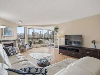 Experience breathtaking city and harbor views from this stunning living room, featuring a plush white sectional sofa and a stylish glass coffee table.