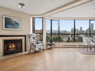 Experience breathtaking city and water views from this stunning living space, complete with a cozy fireplace and elegant wingback chair.