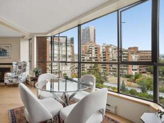 Experience breathtaking city and mountain views from this stunning condo, featuring a modern dining area with a glass-top table and comfortable seating.