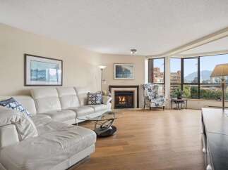Experience luxury living in this spacious condo featuring a modern white leather sectional sofa and a cozy fireplace.