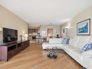 Experience modern living in this spacious open-concept condo featuring a sleek white sectional sofa and a stylish glass coffee table.