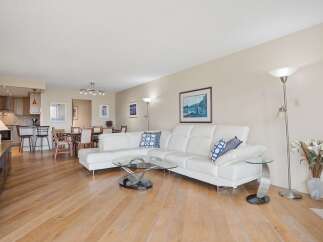 Experience modern living in this spacious open-concept condo featuring a sleek white sectional sofa and a stylish glass coffee table.