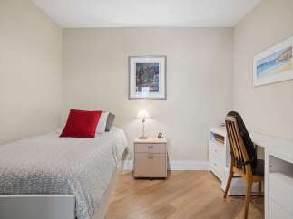 This cozy bedroom features a comfortable single bed adorned with a vibrant red throw pillow and a stylish grey patterned duvet.