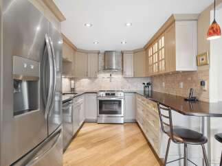 This U-shaped kitchen features sleek stainless steel appliances, including a side-by-side refrigerator and a modern range.