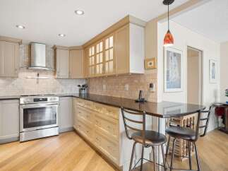 This kitchen boasts elegant cabinetry, a sleek stainless steel range with a modern hood, and a beautiful tiled backsplash.
