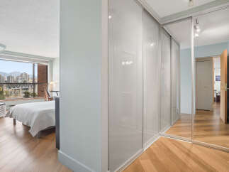 Experience breathtaking city and mountain views from this stunning bedroom, featuring a large window and a comfortable bed.