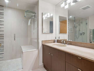 Experience modern luxury in this stunning bathroom featuring a spacious glass-enclosed shower with elegant tilework and a convenient built-in bench.