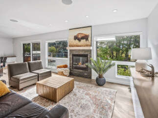 Experience modern living in this spacious great room, featuring a cozy stone fireplace and large windows that flood the space with natural light.
