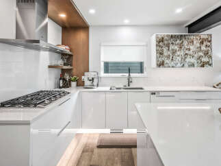 Experience modern luxury in this stunning kitchen, featuring sleek white cabinetry and a professional-grade gas range.