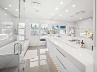 Experience luxury in this modern bathroom featuring a freestanding soaking tub and a spacious double vanity with sleek white countertops.