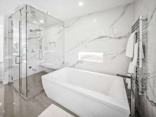 Experience luxury in this modern bathroom featuring a freestanding soaking tub and a spacious glass-enclosed shower with marble tile accents.