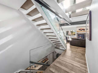 Experience modern luxury with this stunning staircase featuring floating wooden treads and sleek glass railings.