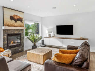 Experience modern living with this stunning living room featuring a captivating stone fireplace and a large buffalo artwork.