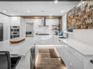 Experience luxury in this modern kitchen featuring sleek white cabinetry, integrated stainless steel appliances, and a spacious quartz island perfect for entertaining.