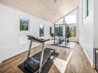 Elevate your fitness routine in this modern home gym, featuring a spacious power rack with weights and a treadmill.