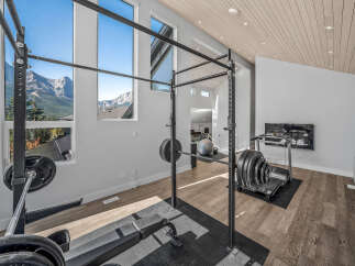 Elevate your fitness routine in this stunning home gym, boasting a full squat rack with weights and a treadmill.