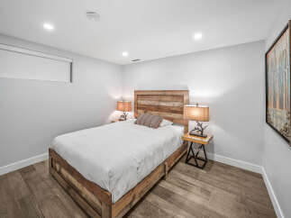 This modern bedroom features a rustic wooden bed frame and headboard, complemented by a neutral color palette and warm ambient lighting.