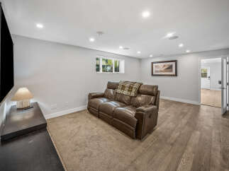 Experience ultimate comfort in this modern basement living area, featuring a plush leather reclining sofa perfect for movie nights.
