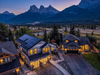 Experience luxury living in this stunning modern home, featuring a sleek design with solar panels and large, illuminated windows.