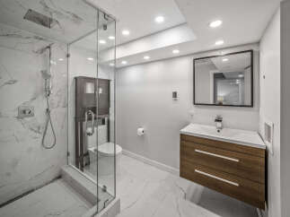 Experience modern luxury in this stunning bathroom featuring a spacious walk-in shower with marble tile and a rainfall showerhead.