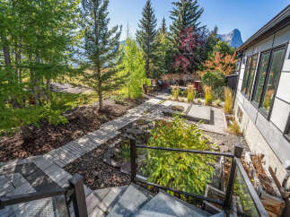 Discover this stunning mountain property featuring a beautifully landscaped backyard with a modern hot tub and a winding stone pathway.